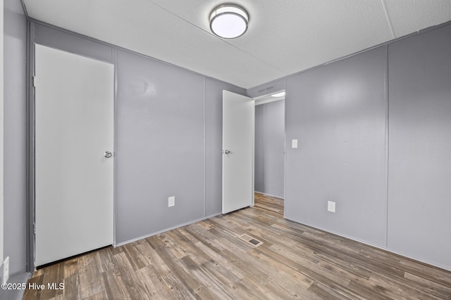 unfurnished bedroom with visible vents, a textured ceiling, and wood finished floors