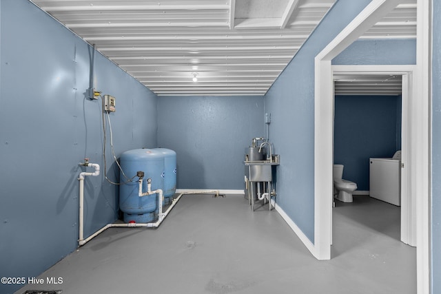 below grade area with baseboards, a sink, and washer / dryer
