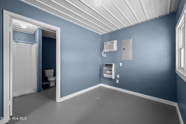 clothes washing area with an AC wall unit, heating unit, baseboards, and electric panel