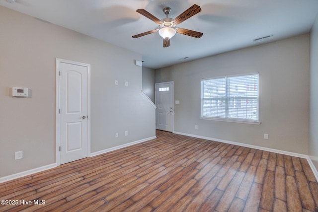 unfurnished room featuring a ceiling fan, wood finished floors, visible vents, and baseboards