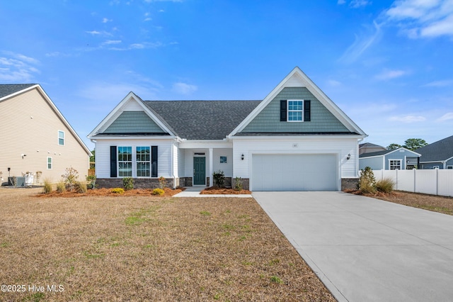 craftsman-style home with stone siding, a front lawn, central AC, and concrete driveway