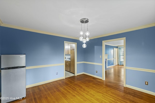 unfurnished dining area featuring baseboards, ornamental molding, and wood finished floors