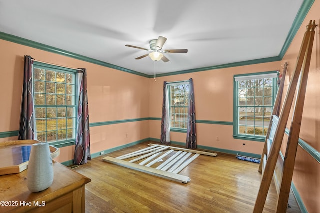 unfurnished room with baseboards, ornamental molding, ceiling fan, and wood finished floors