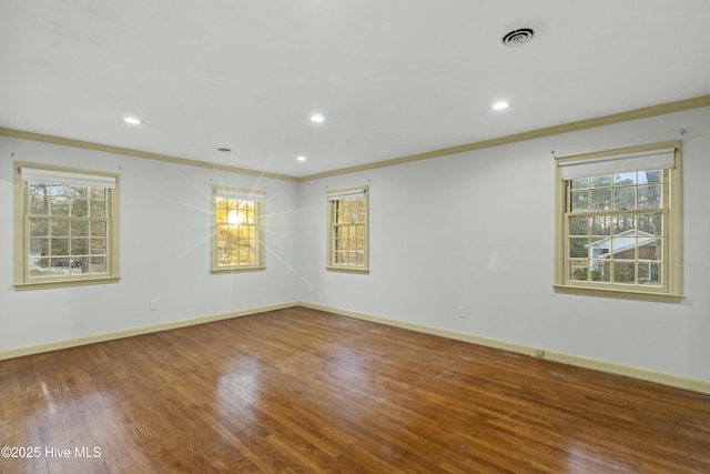 unfurnished room with crown molding, baseboards, plenty of natural light, and wood finished floors