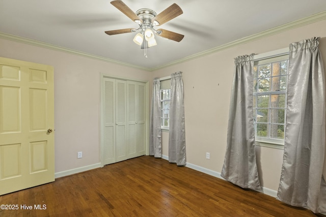 unfurnished bedroom featuring ceiling fan, dark wood-type flooring, crown molding, and a closet