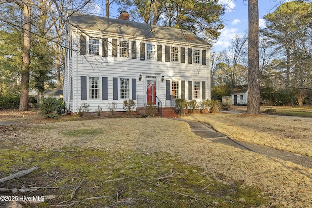 colonial home with a front yard and an outbuilding