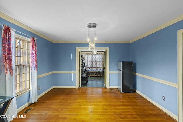 unfurnished dining area featuring crown molding, baseboards, wood finished floors, and visible vents