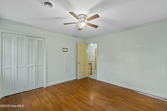 unfurnished bedroom featuring hardwood / wood-style floors, ceiling fan, a closet, and crown molding