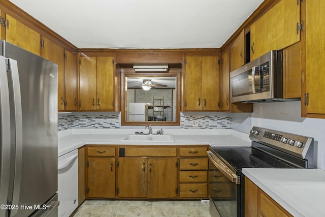 kitchen featuring brown cabinetry, a sink, appliances with stainless steel finishes, and tasteful backsplash
