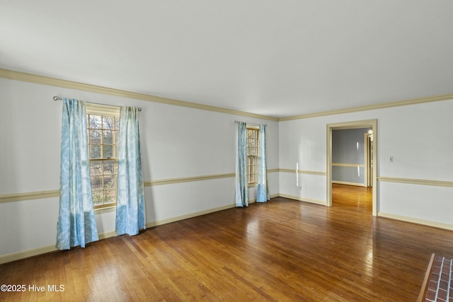 empty room with crown molding, baseboards, and wood finished floors