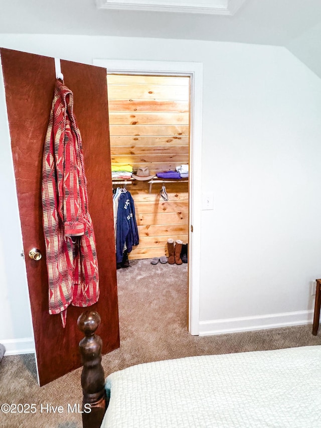 hallway with lofted ceiling, carpet, and baseboards