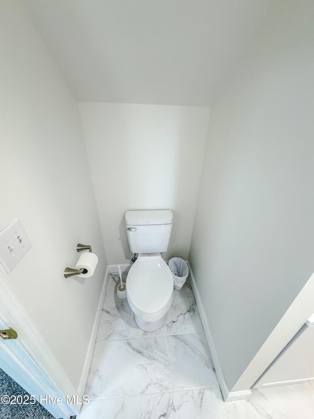 bathroom featuring toilet, marble finish floor, and baseboards