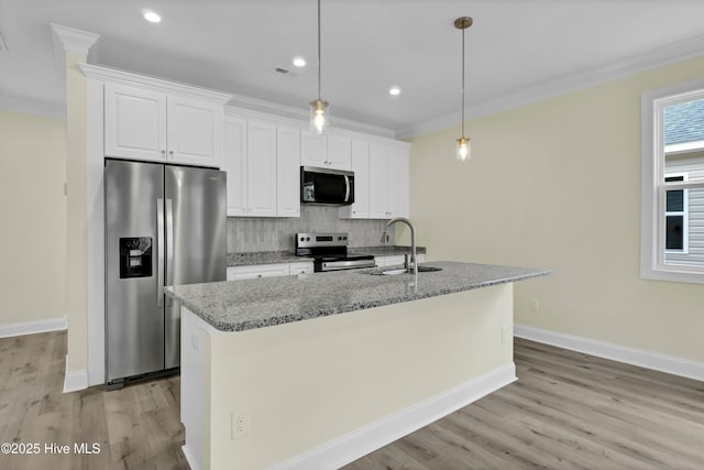 kitchen with an island with sink, white cabinetry, decorative light fixtures, light stone countertops, and appliances with stainless steel finishes