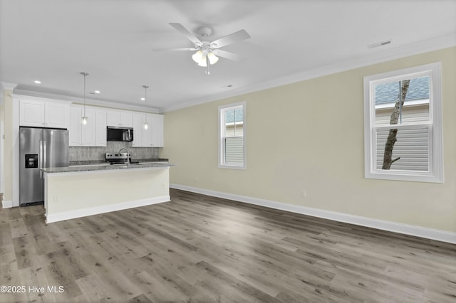 kitchen with white cabinetry, a center island with sink, decorative light fixtures, ornamental molding, and appliances with stainless steel finishes