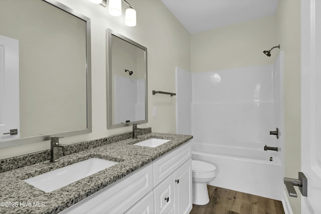 full bathroom featuring wood-type flooring, vanity, shower / bathtub combination, and toilet