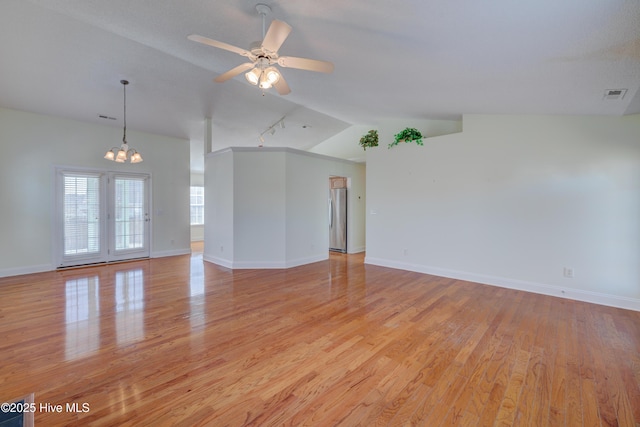 empty room featuring lofted ceiling, visible vents, light wood-style floors, baseboards, and ceiling fan with notable chandelier