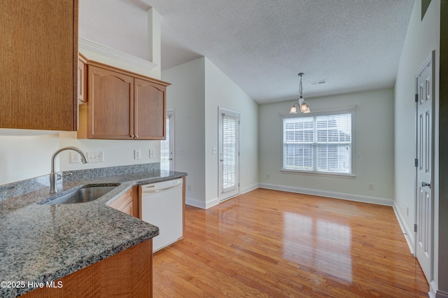 kitchen with dark stone countertops, white dishwasher, a textured ceiling, light wood-type flooring, and a sink