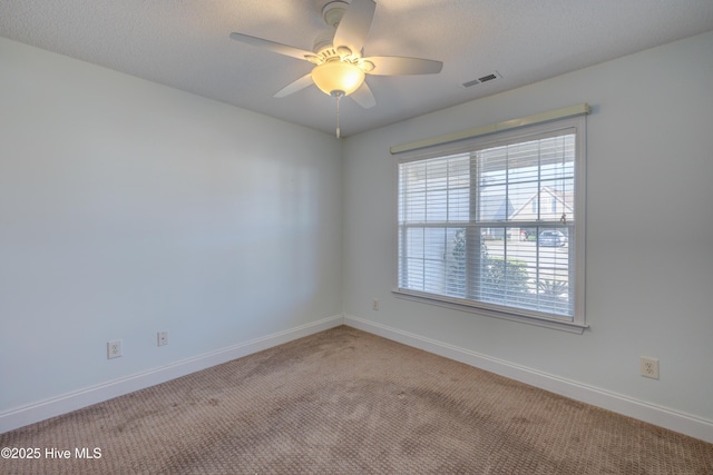 carpeted spare room with baseboards, visible vents, ceiling fan, and a textured ceiling