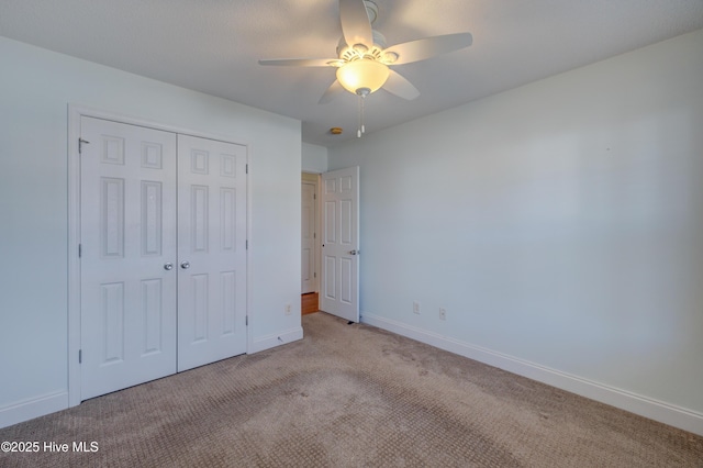 unfurnished bedroom with carpet floors, ceiling fan, baseboards, and a closet