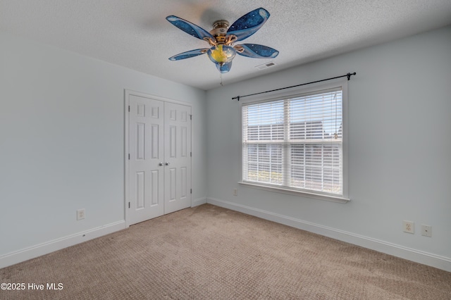 unfurnished bedroom with a textured ceiling, carpet, visible vents, and baseboards