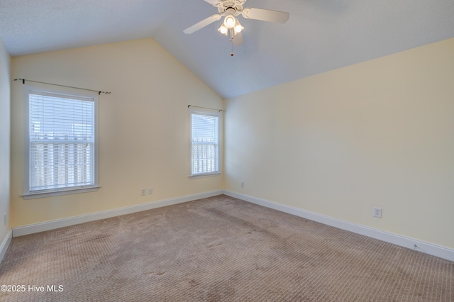 carpeted empty room featuring vaulted ceiling, baseboards, and ceiling fan