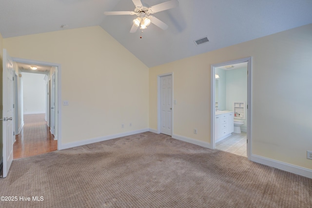 unfurnished bedroom with light colored carpet, visible vents, connected bathroom, vaulted ceiling, and baseboards