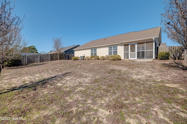 back of property with a fenced backyard, a sunroom, and central air condition unit