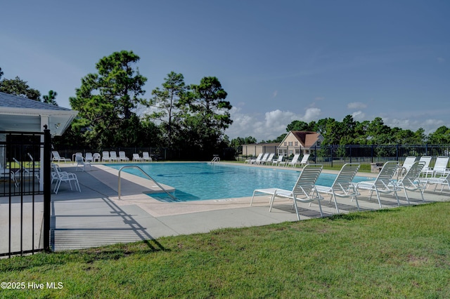 community pool featuring a patio area, fence, and a yard