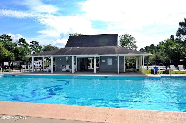 pool featuring a patio area, fence, and an outdoor structure