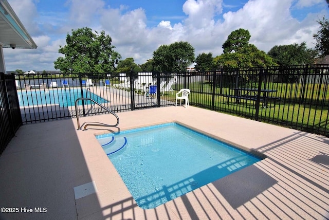 community pool featuring a lawn, a patio area, and fence