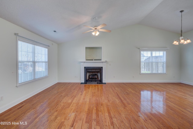 unfurnished living room featuring lofted ceiling, light wood-style flooring, a fireplace with flush hearth, visible vents, and baseboards