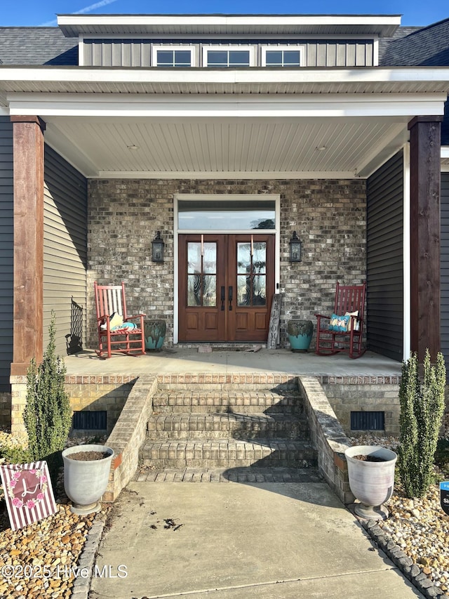 property entrance with covered porch and french doors