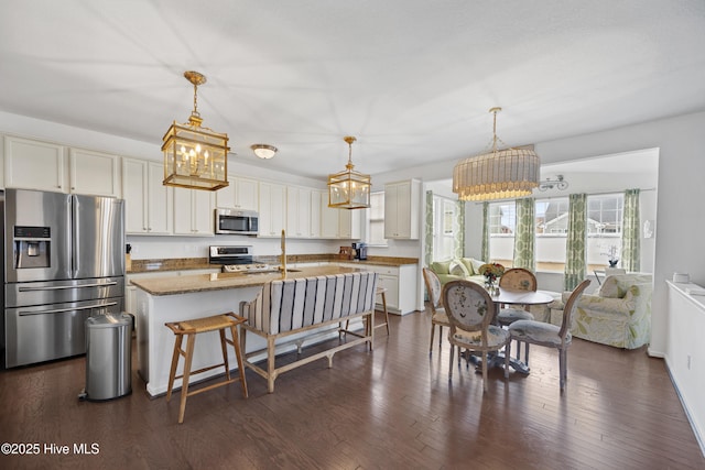 kitchen with stainless steel appliances, light stone countertops, a notable chandelier, and dark wood finished floors