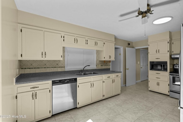 kitchen with cream cabinetry, tasteful backsplash, dark countertops, appliances with stainless steel finishes, and a sink