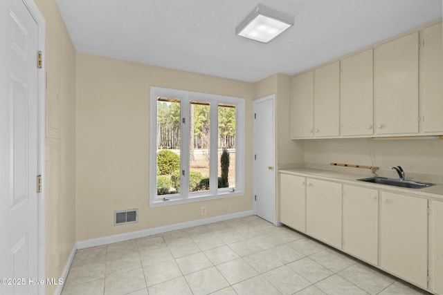 kitchen with light countertops, a sink, visible vents, and baseboards