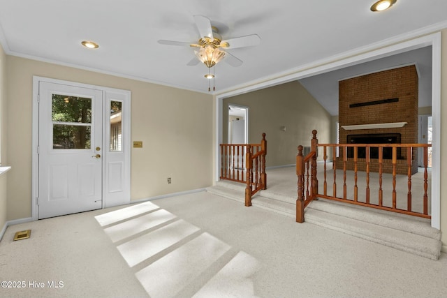 carpeted entryway with baseboards, a ceiling fan, crown molding, a fireplace, and recessed lighting