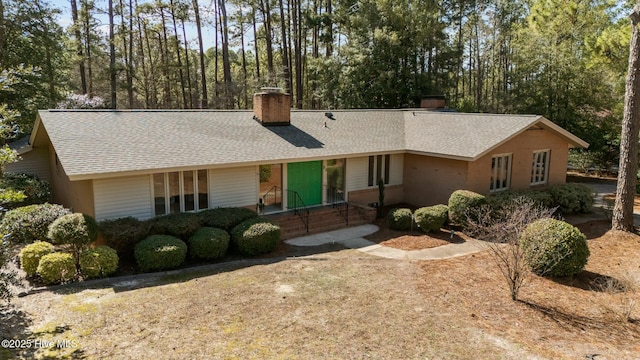 single story home with a shingled roof and a chimney