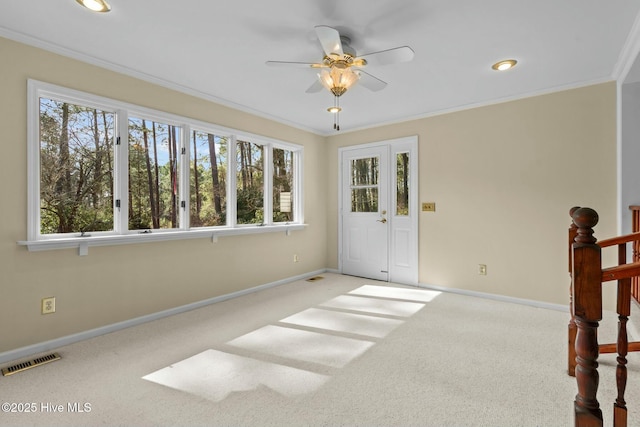 unfurnished room featuring plenty of natural light, light colored carpet, visible vents, and crown molding