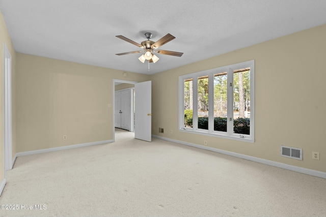 unfurnished room featuring light carpet, baseboards, visible vents, and ceiling fan