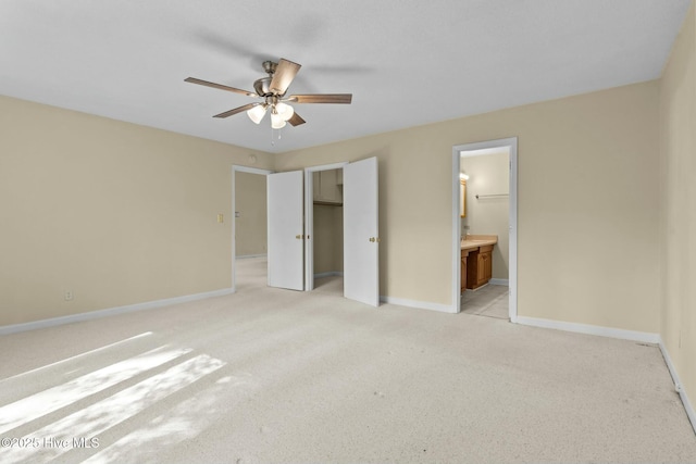 unfurnished bedroom featuring a closet, light carpet, ceiling fan, ensuite bath, and baseboards