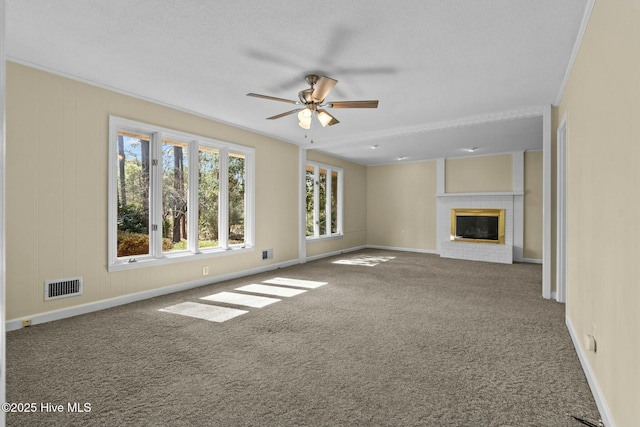 unfurnished living room with visible vents, a ceiling fan, ornamental molding, carpet floors, and a brick fireplace