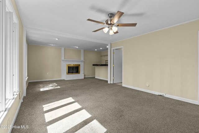 unfurnished living room featuring a brick fireplace, carpet, baseboards, and crown molding