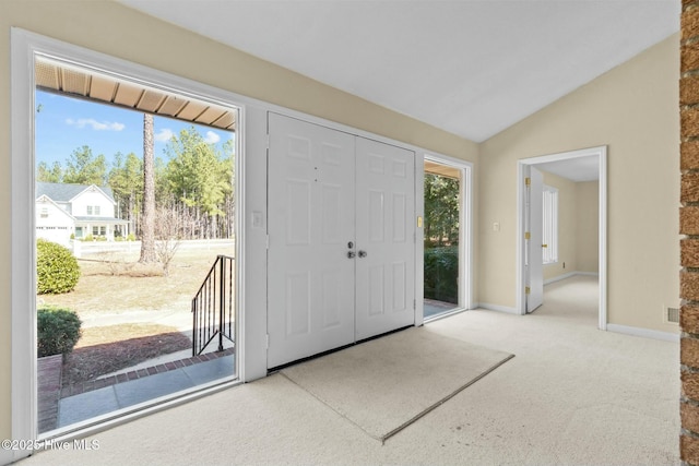 entryway with a healthy amount of sunlight, baseboards, vaulted ceiling, and light colored carpet