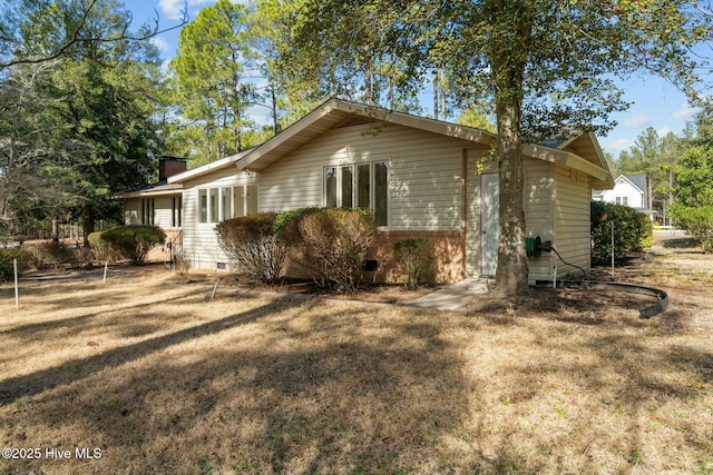 view of side of property with a chimney and a yard