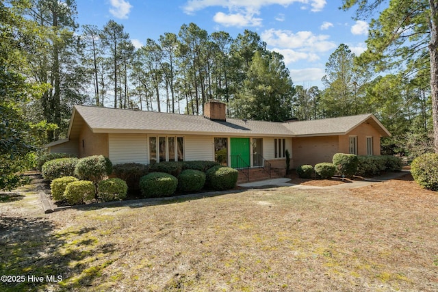 ranch-style home with a front yard and a chimney