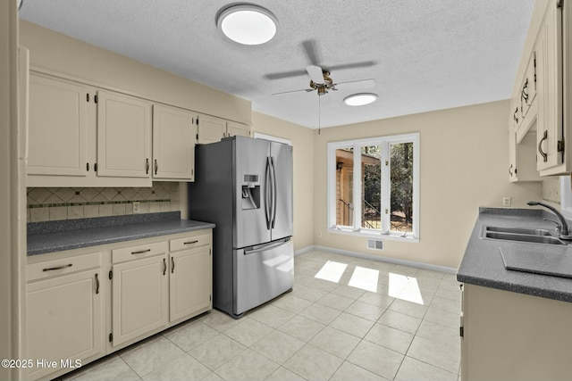 kitchen with tasteful backsplash, dark countertops, a sink, ceiling fan, and stainless steel fridge with ice dispenser