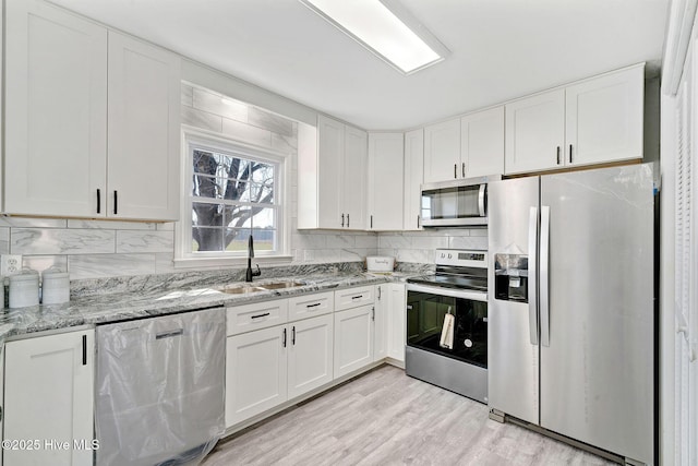 kitchen with appliances with stainless steel finishes, white cabinets, and a sink