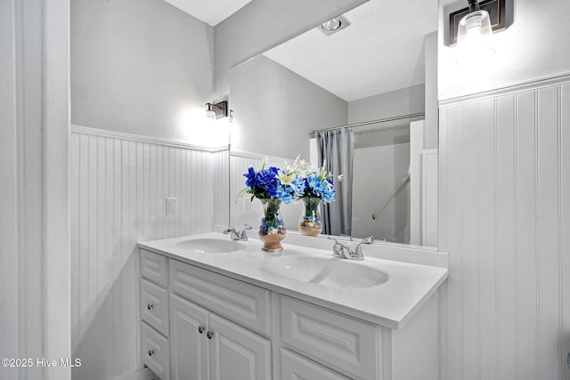 full bath featuring double vanity, wainscoting, and a sink