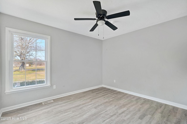 empty room with ceiling fan, light wood-type flooring, visible vents, and baseboards