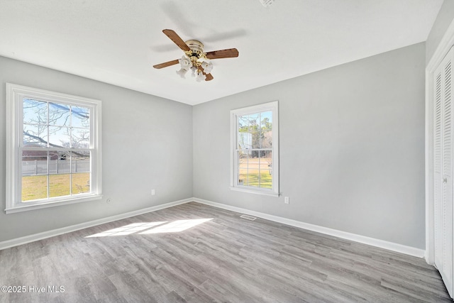 unfurnished room featuring plenty of natural light, baseboards, light wood-style flooring, and a ceiling fan